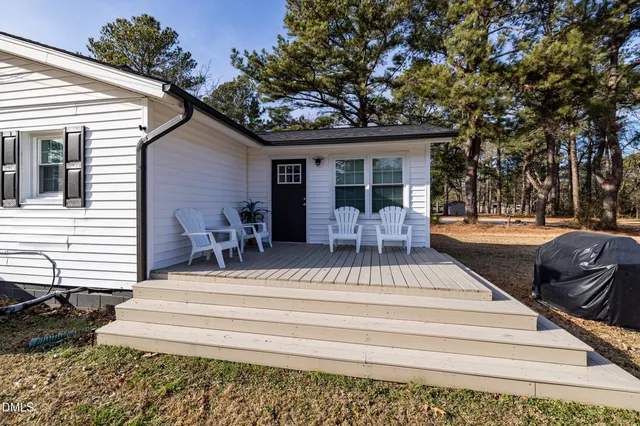 a view of a patio with table and chairs potted plants and floor to ceiling window