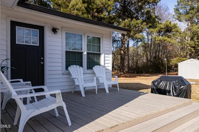 a view of a patio with table and chairs with wooden floor and fence