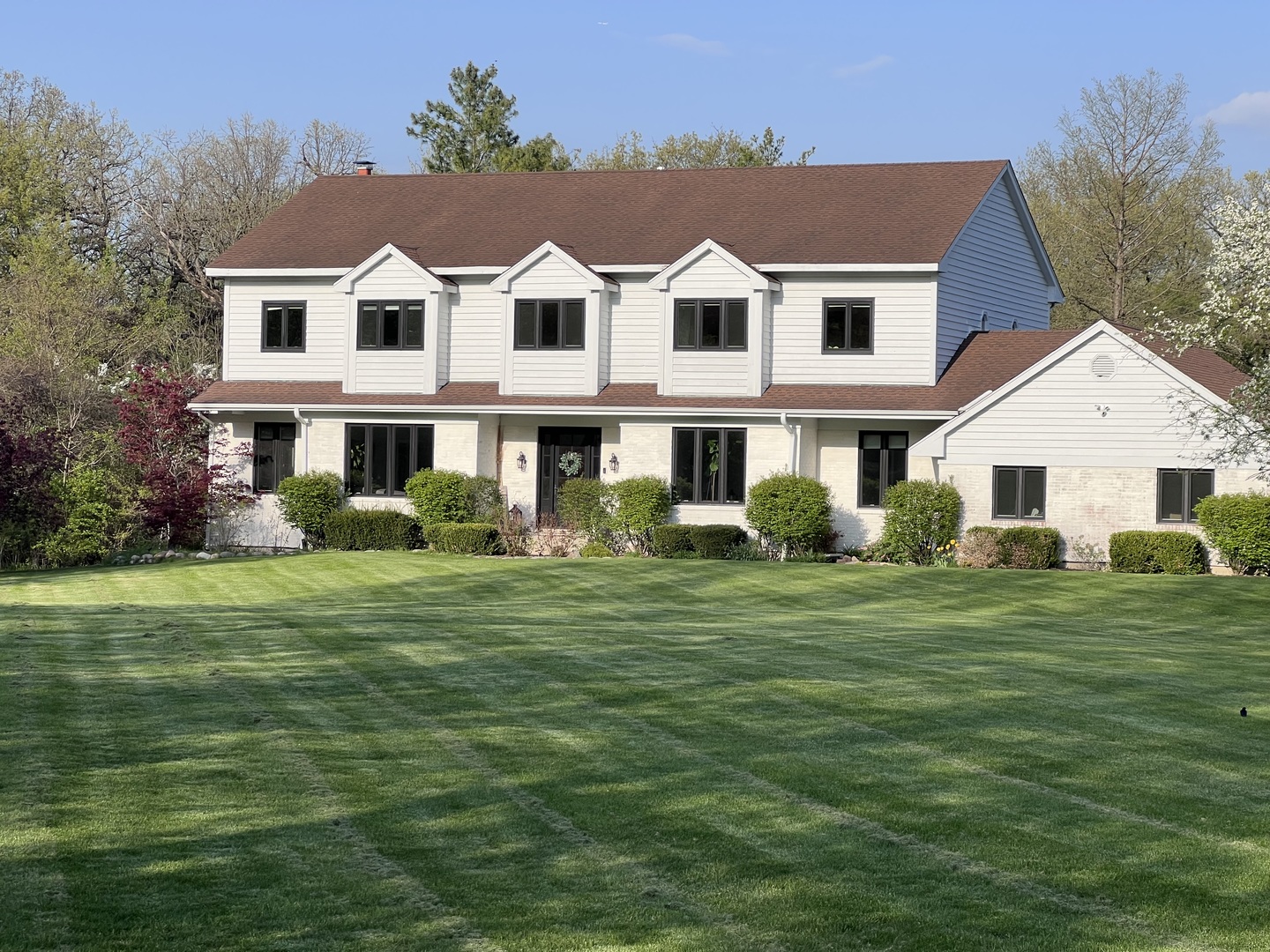 a view of a big house with a big yard and large trees