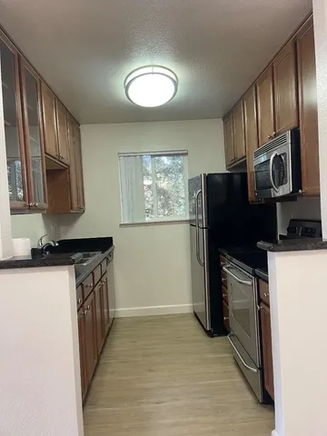 a kitchen with stainless steel appliances granite countertop a refrigerator a stove a sink and a microwave