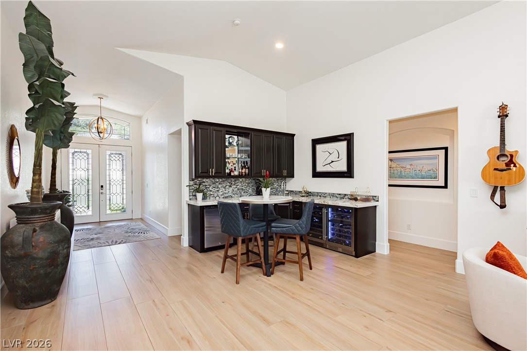 2256 Dogwood Ranch Avenue Henderson, NV 89052 - Photo 25 of 51 Blonde wood flooring creates a welcoming ambiance, leading past a chic bar area to a grand entryway.