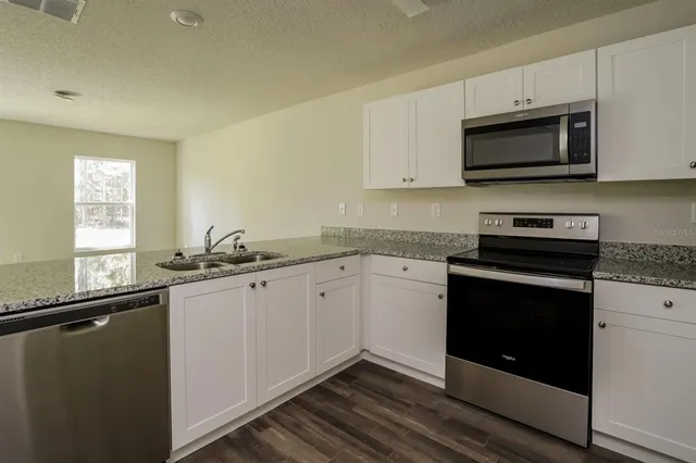 a kitchen with granite countertop a sink and a stove top oven