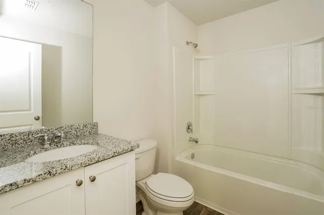 a bathroom with a granite countertop sink a toilet and shower