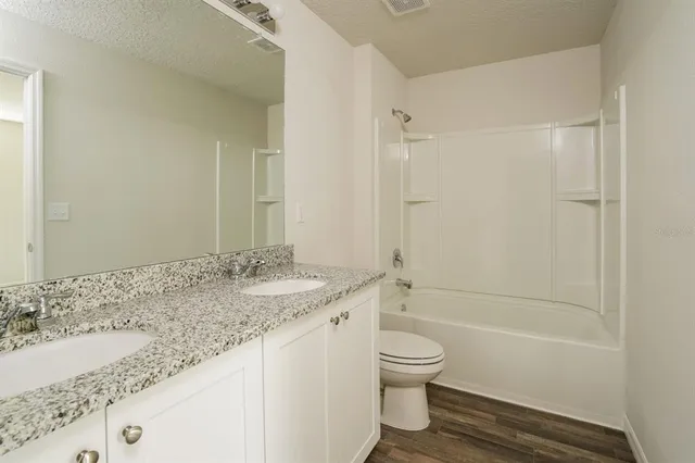 a bathroom with a granite countertop sink a toilet and shower