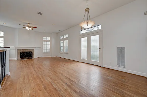 an empty room with wooden floor fireplace and windows