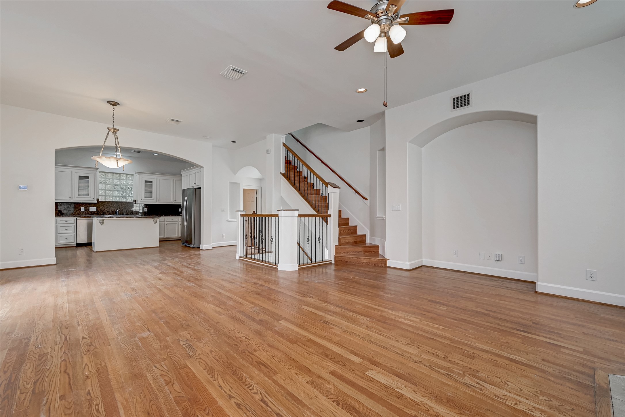 5410 Rose Street Houston, TX 77007 - Photo 14 of 41 a view of an empty room with wooden floor a ceiling fan and kitchen space