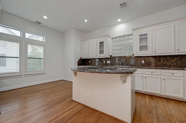 a kitchen with granite countertop white cabinets sink and wooden floor