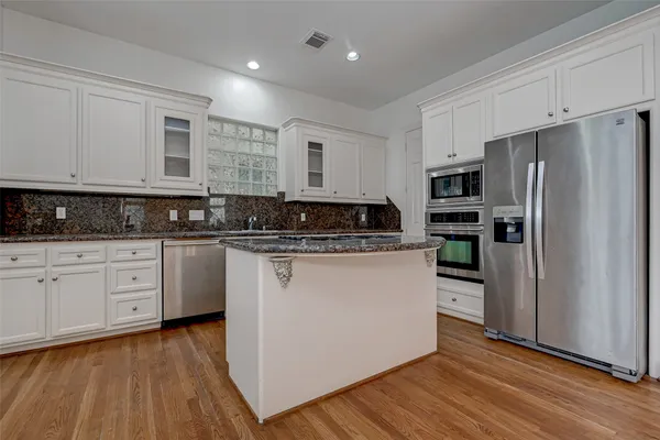 a kitchen with stainless steel appliances granite countertop a refrigerator a stove a sink and white cabinets