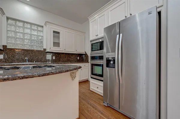 a kitchen with stainless steel appliances granite countertop a refrigerator a stove and a sink with wooden cabinets