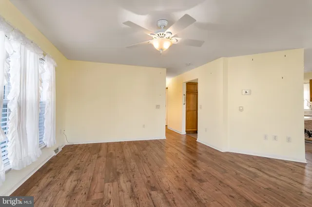 a view of an empty room with wooden floor and a window