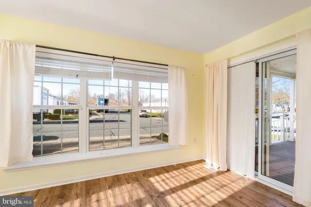 a view of a hallway with wooden floor and a kitchen
