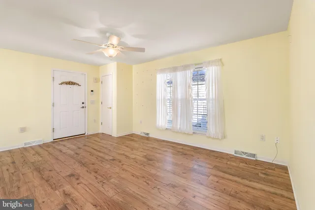an empty room with windows and fan