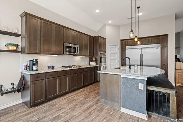 a kitchen with stainless steel appliances granite countertop a stove a sink dishwasher a refrigerator and a oven with wooden floor