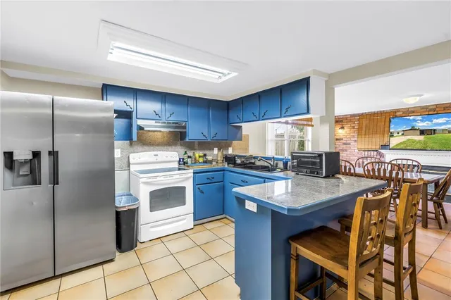a kitchen with stainless steel appliances kitchen island granite countertop a table chairs sink and cabinets