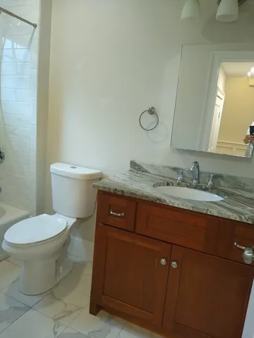 a bathroom with a granite countertop toilet and a sink