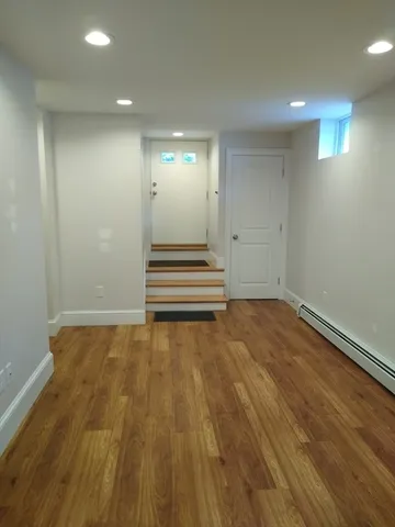 a view of an empty room with wooden floor and stairs