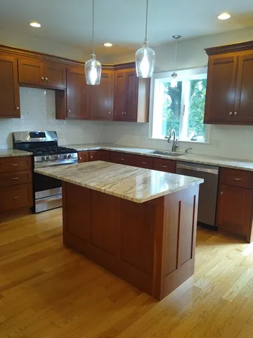 a large kitchen with wooden floors and stainless steel appliances