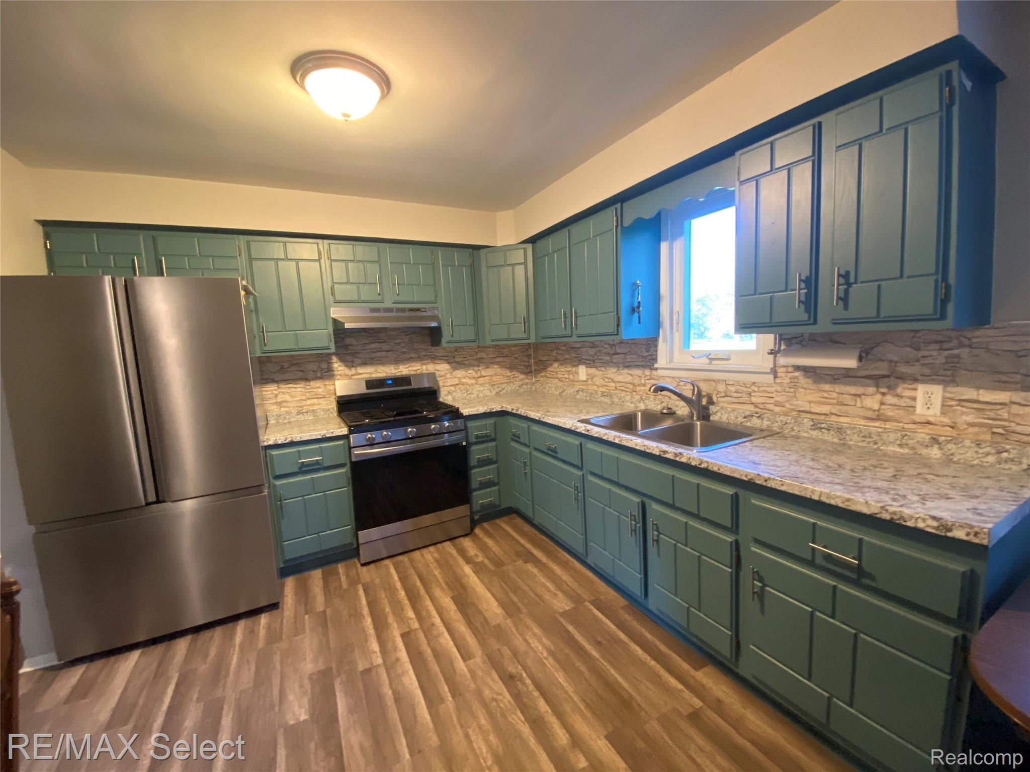 6169 Johnson Road Flushing, MI 48433 - Photo 2 of 28 Kitchen with green cabinetry, stainless steel appliances, dark wood-style flooring, and tasteful backsplash