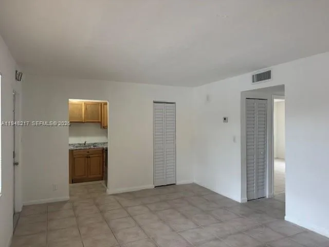 an empty room with kitchen and refrigerator