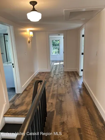 a view of a hallway to a livingroom with furniture wooden floor and window