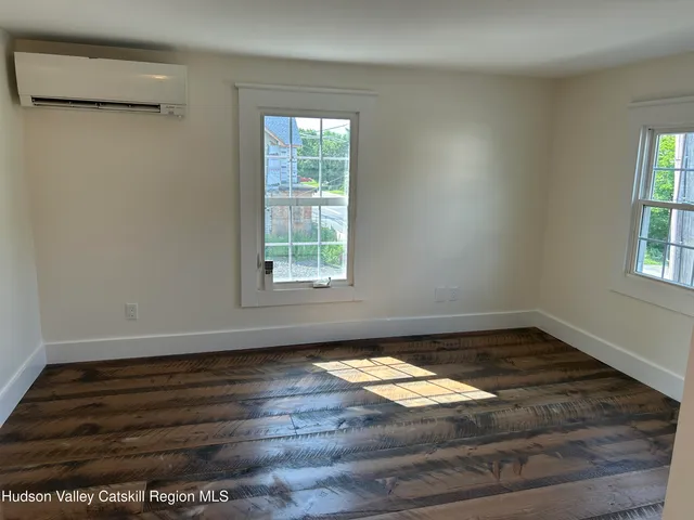 an empty room with wooden floor closet and windows