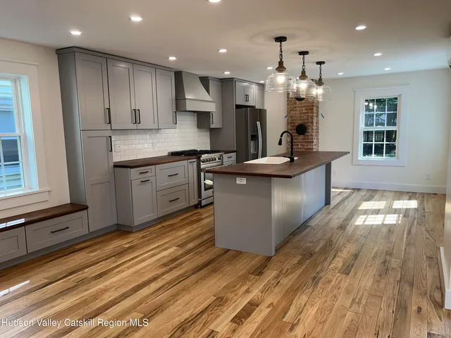 a kitchen with stainless steel appliances granite countertop a sink a stove and a wooden floors