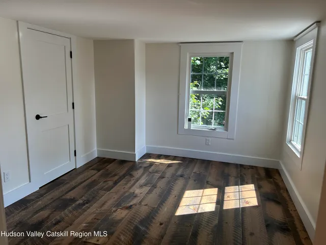 a view of hallway with window and wooden floor