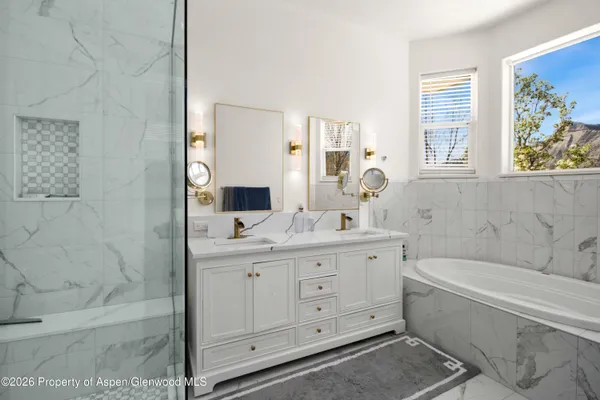 a bathroom with a double vanity sink a large mirror a bathtub and shower