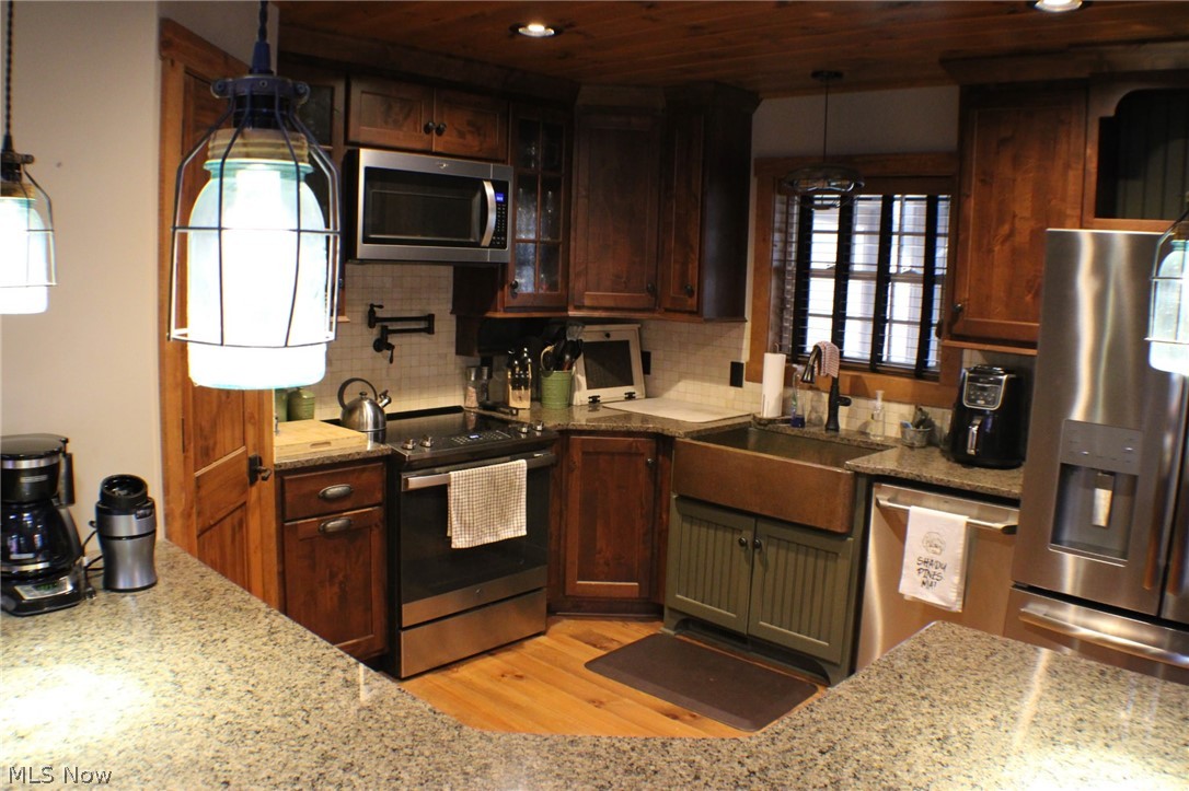3989 Court Road Wakeman, OH 44889 - Photo 7 of 36 Kitchen featuring light stone counters, stainless steel appliances, pendant lighting, light wood-type flooring, and decorative backsplash