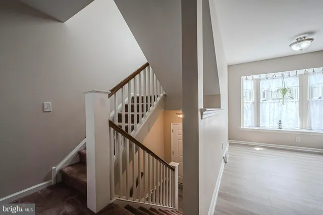 a view of staircase with wooden floor and white walls