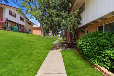 a view of a house with a big yard potted plants and a large tree