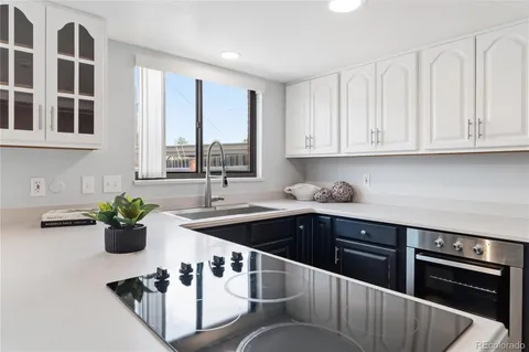 a kitchen with stainless steel appliances granite countertop a sink dishwasher and white cabinets with wooden floor