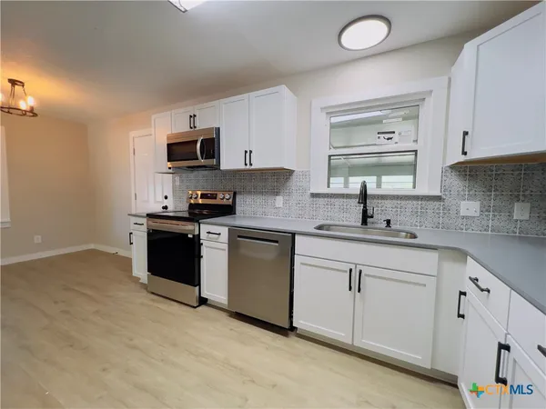 a kitchen with white cabinets appliances and sink