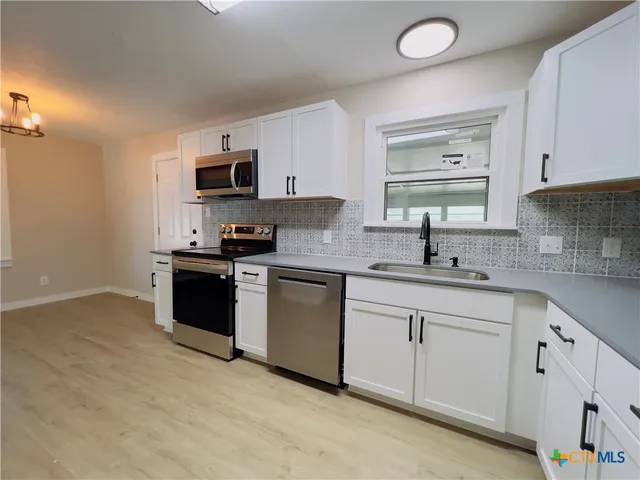 a kitchen with white cabinets appliances and sink