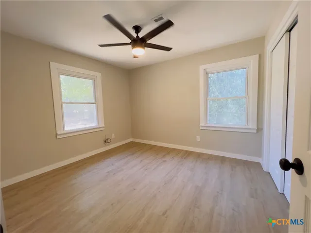 a view of a big room with wooden floor and windows