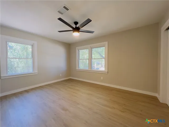 a view of an empty room with wooden floor and a window
