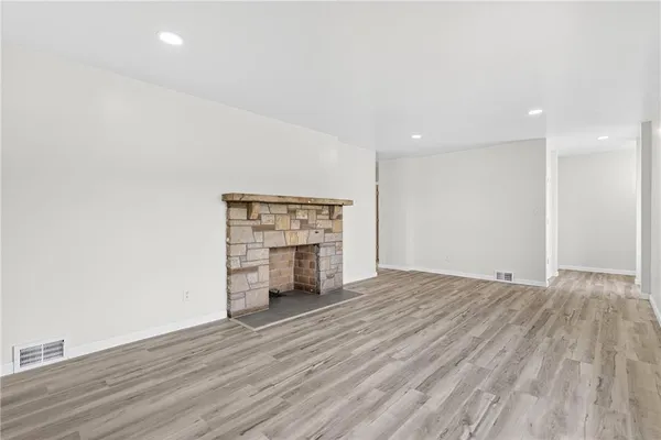 a view of empty room with wooden floor and fireplace