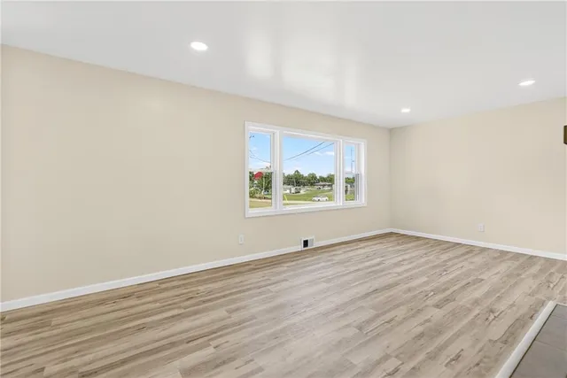 an empty room with wooden floor and window
