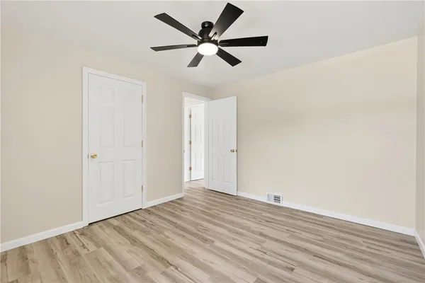 an empty room with wooden floor and ceiling fan