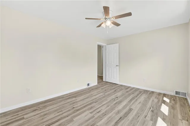 an empty room with wooden floor and ceiling fan