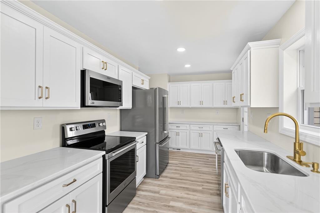 545 Vanderbilt Road Connellsville, PA 15425 - Photo 28 of 49 a kitchen with stainless steel appliances granite countertop a sink a stove top oven a refrigerator with white cabinets and wooden floor