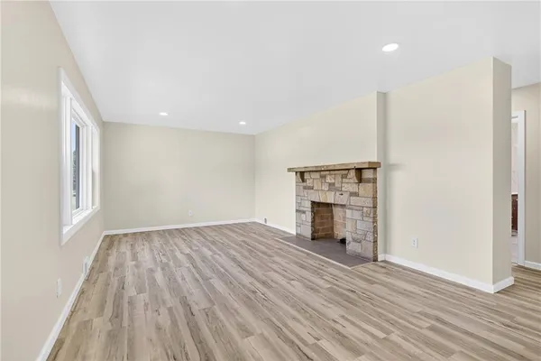 an empty room with wooden floor fireplace and windows
