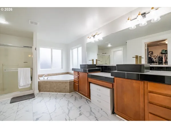 a large white kitchen with kitchen island a sink a counter space and stainless steel appliances