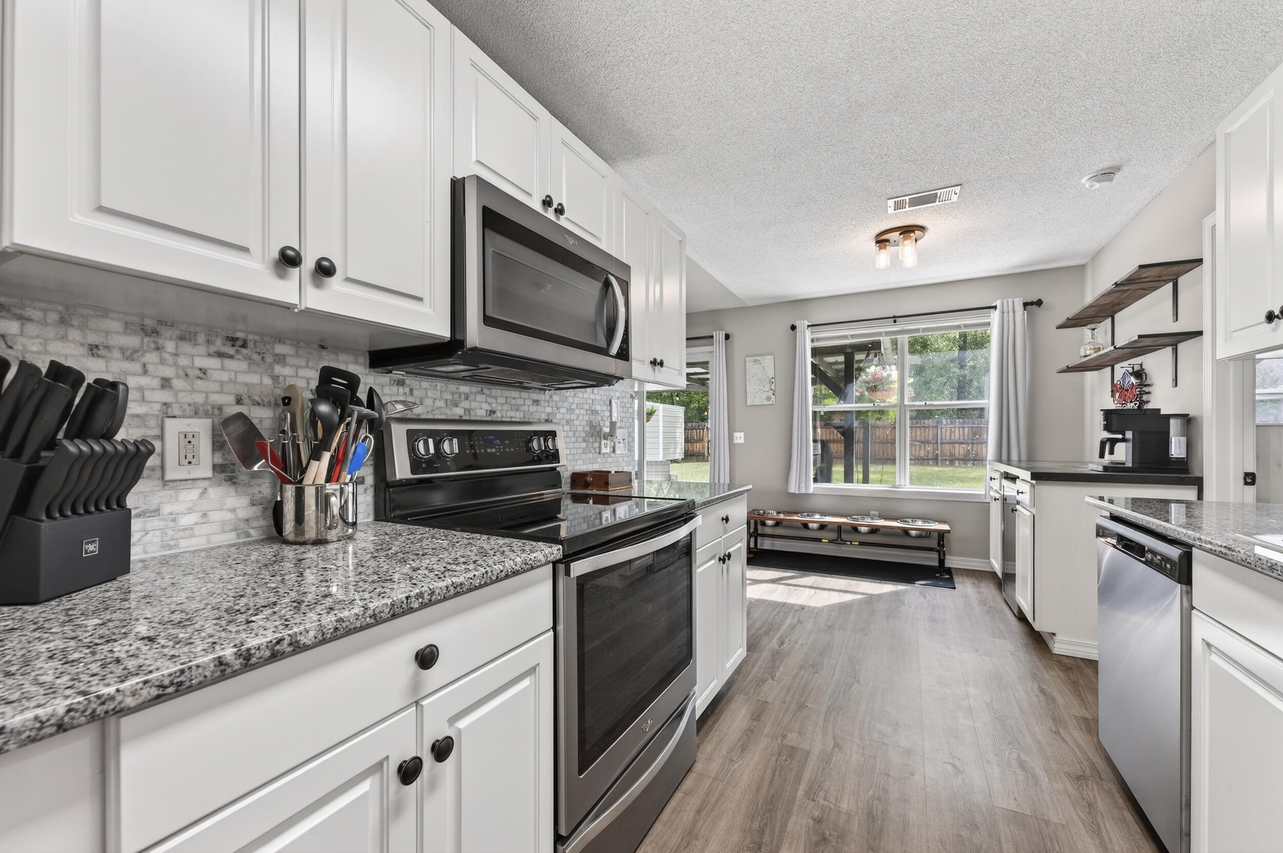 4331 Crosswind Drive Milton, FL 32583 - Photo 16 of 50 a kitchen with granite countertop a stove top oven a sink dishwasher and a microwave oven with white cabinets