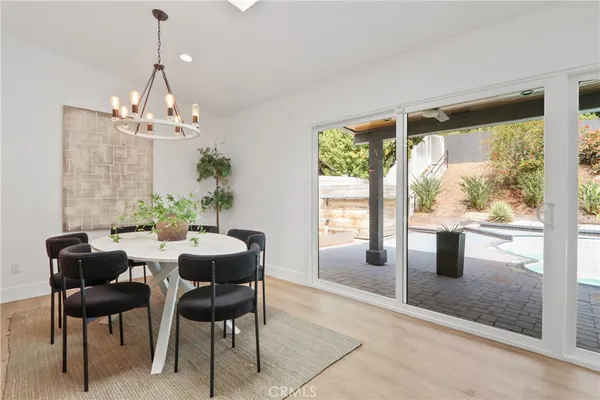 a dining room with wooden floor a chandelier a glass table and chairs