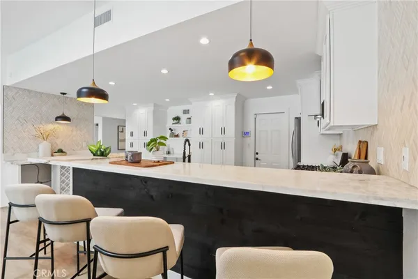 a kitchen with stainless steel appliances granite countertop a sink a stove a dining table and chairs