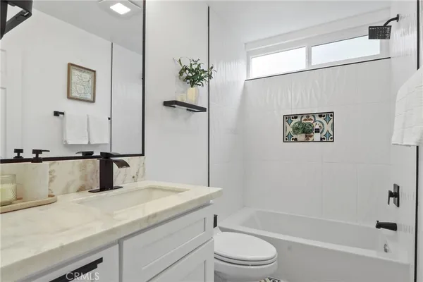 a bathroom with a granite countertop sink a toilet and shower