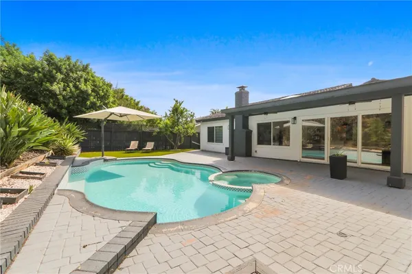 a view of a house with backyard sitting area and swimming pool