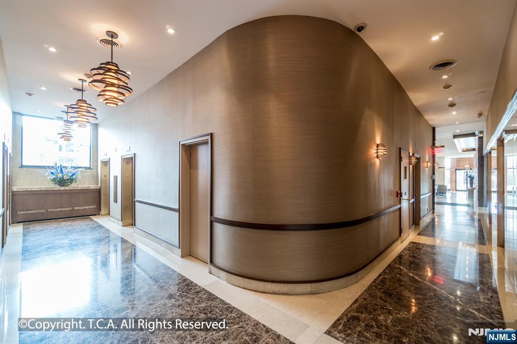200 Old Palisade Road, Unit 25D Fort Lee, NJ 07024 - Photo 26 of 30 a view of a hallway with a dining table and chandelier