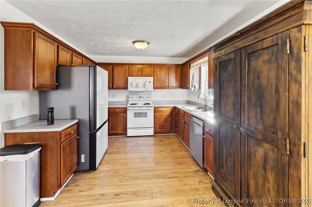 a kitchen with stainless steel appliances granite countertop a stove top oven a sink dishwasher and a refrigerator